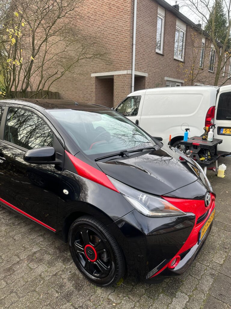 Professionele mobiele autodetailer brengt wax aan op een auto op de oprit van een klant.