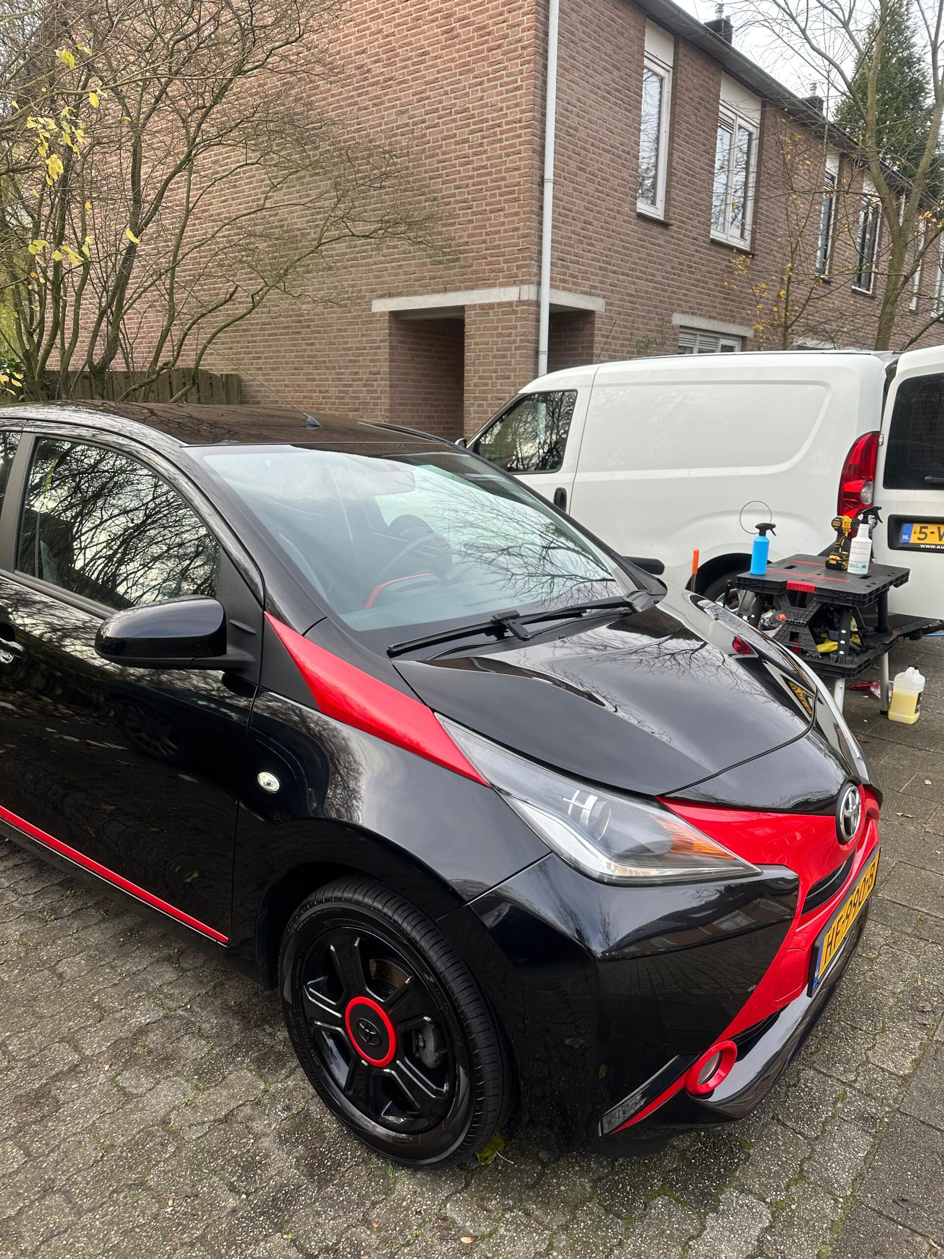 Professionele mobiele autodetailer brengt wax aan op een auto op de oprit van een klant.